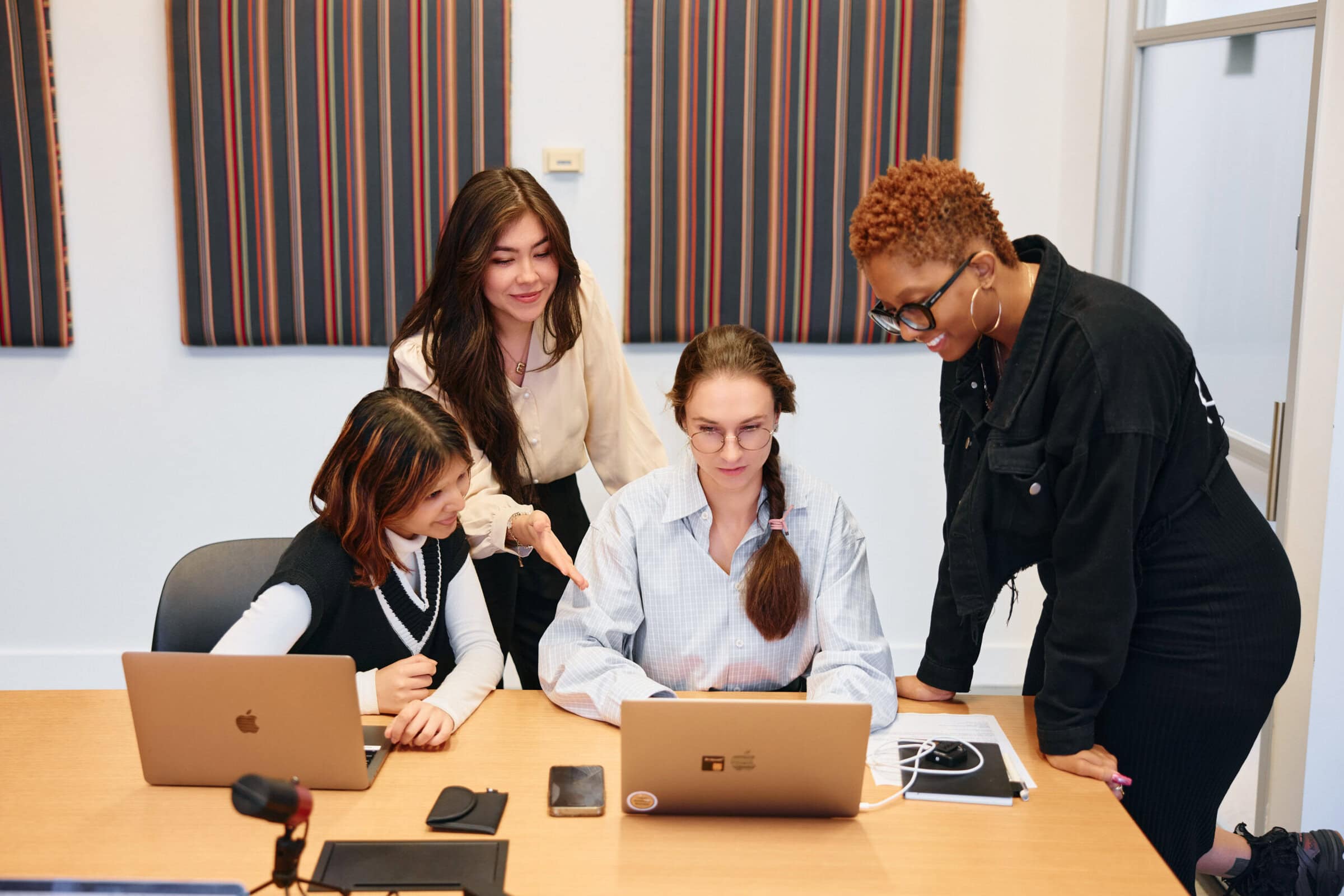 Evoto Mixed group of women in a room, sitting at a table and looking at a laptop